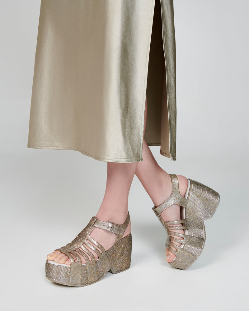 Model's legs wearing a pair of glitter gold  Station 79 platform heels with ankle strap