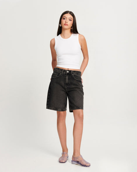 Model in black jean shorts and white tank wearing a pair of clear Possession Pescura + Scholl fisherman sandals with white bottom sole