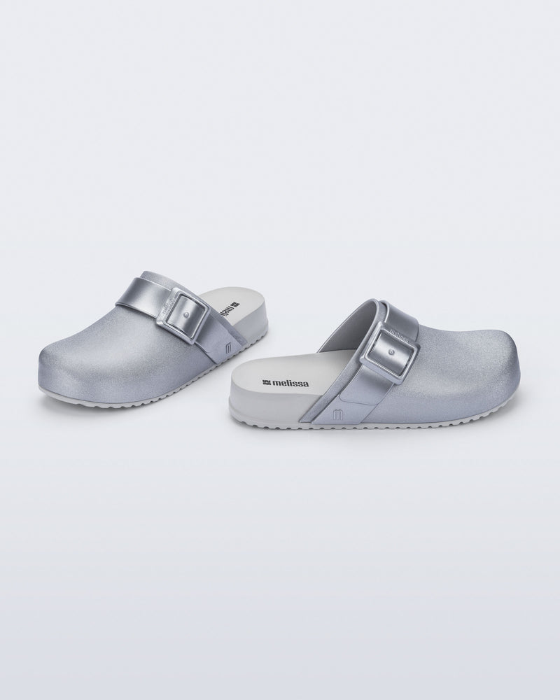 Side and angled view of a pair of silver Cozy Clog with buckle decoration