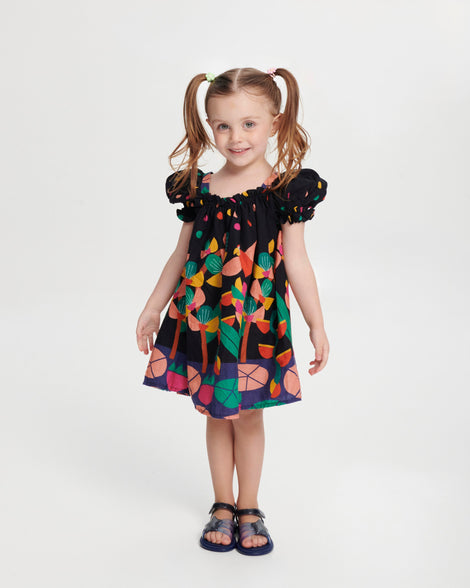 Child model in a black dress with a flower pattern wearing a pair of glitter blue Hip Sky baby sandals with a glitter blue star on top