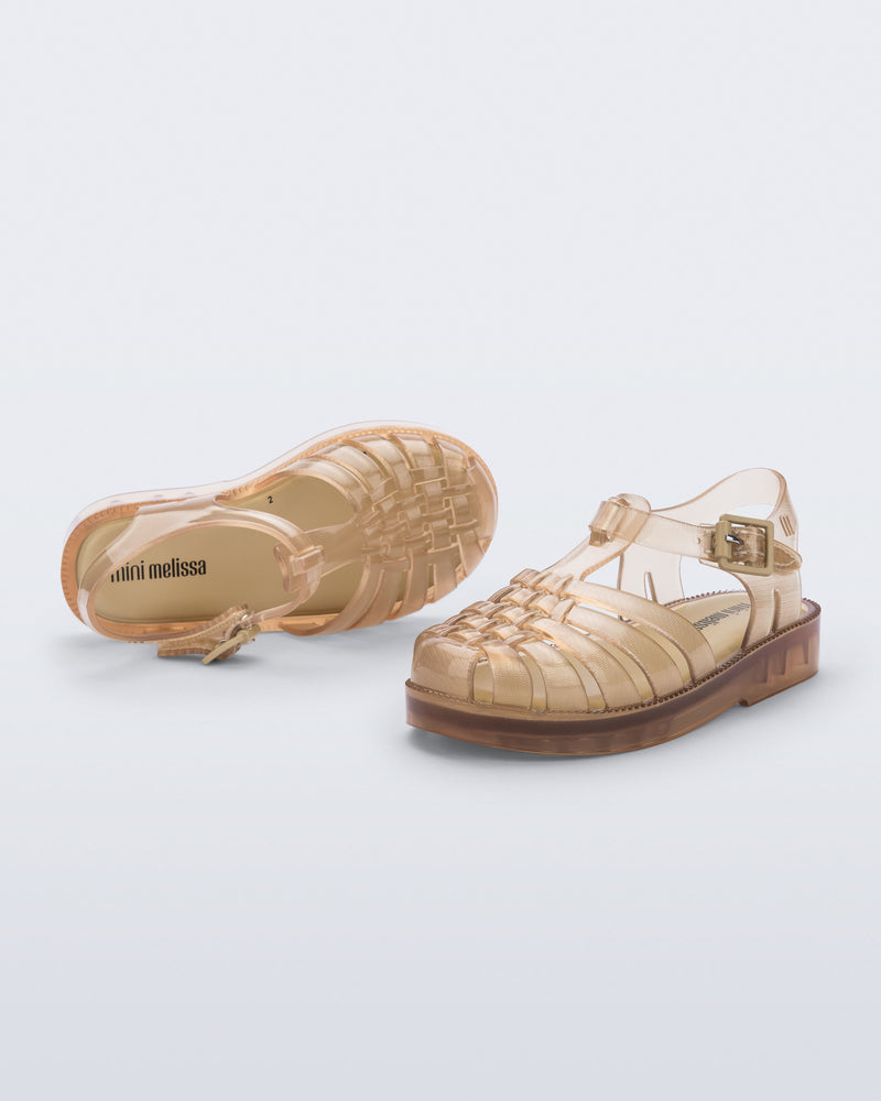 Angled and top view of a pair of clear beige Possession baby sandals