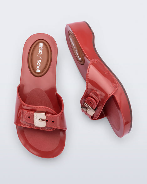Top and side view of a pair of red Pescura Heel + Scholl slides with top buckle