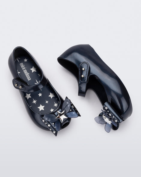 Top and side view of a pair of Mini Melissa Ultragirl peeptoe ballet flats for baby in blue with star printed butterfly bow applique. 