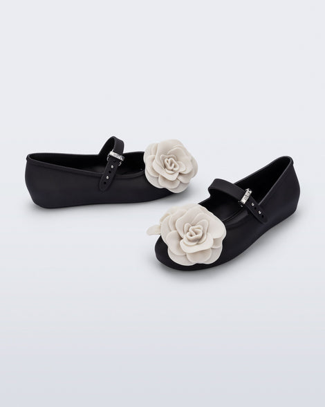 Side and angled view of a pair of black Soft Ballerina Petals kids flat with beige flowers