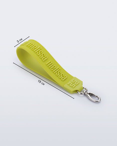 Angled flat view of a green M Lover Charm with the Melissa logo with measurements of 15cm x 3cm