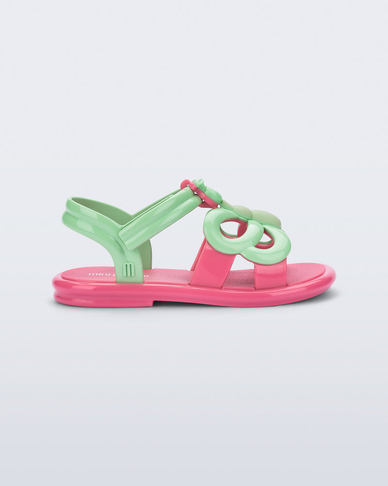 Side view of a green strap, pink sole Hip Butterfly baby sandal