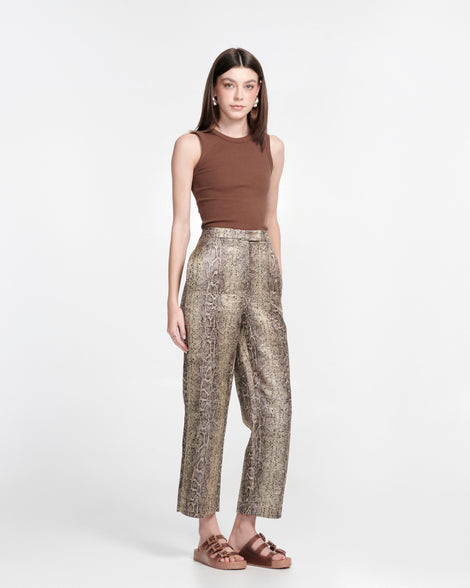 Model in brown shirt and snake print pants wearing a pair of brown Cozy Stripes sandals with transparent brown upper with 3 buckles