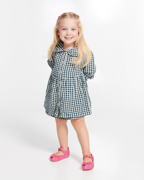 Child model in a black and white checkered dress wearing a pair of pink Ultragirl Colors baby flats with shooting stars
