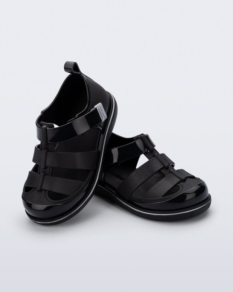 Angled view of a pair of black Smash closed toe baby sandals with grey trim