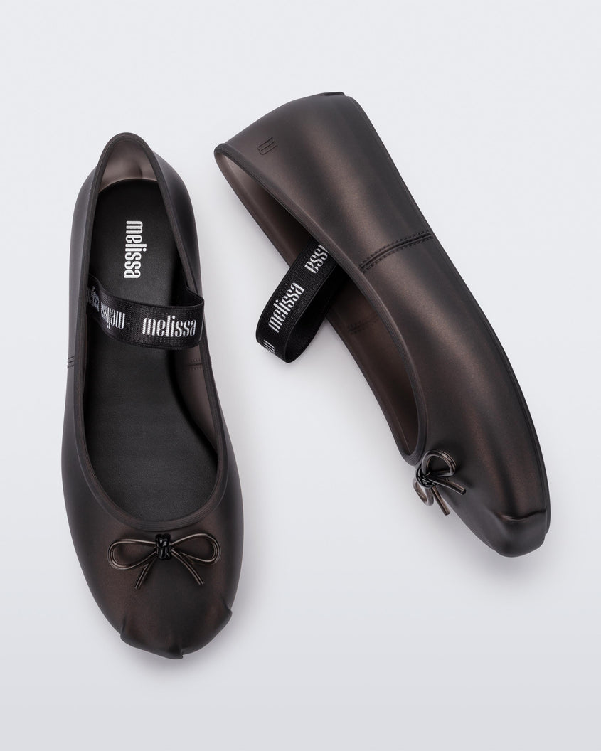 Top and side view of a pair of Melissa Sophie ballet flats in black with M-logo strap and bow applique