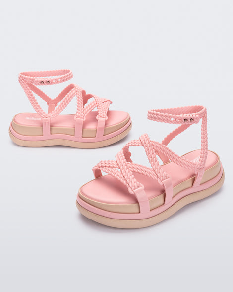 An angled front and side view of a pair of pink Melissa Buzios platform sandals with multiple textured straps that mimic sisal braids across the front of the shoe as well as an ankle strap