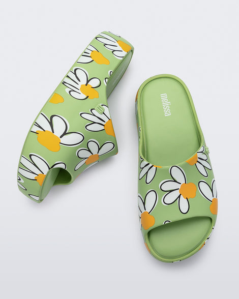 Side and top view of a pair of green Free Print Platform slides with a white and yellow flower print.