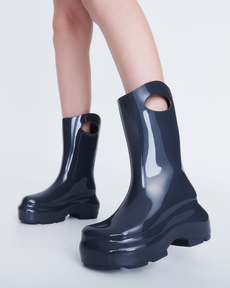 Model's legs wearing a pair of grey Ultra platform rain Boot with circle cutout on top