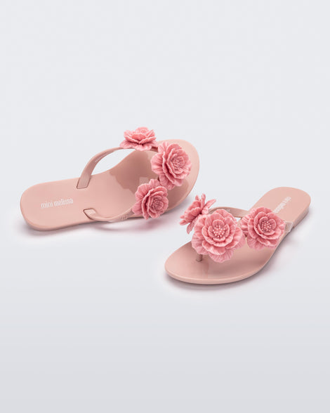 Angled view of a pair of a pink Harmonic Springtime kids flip flop with three pink flowers.