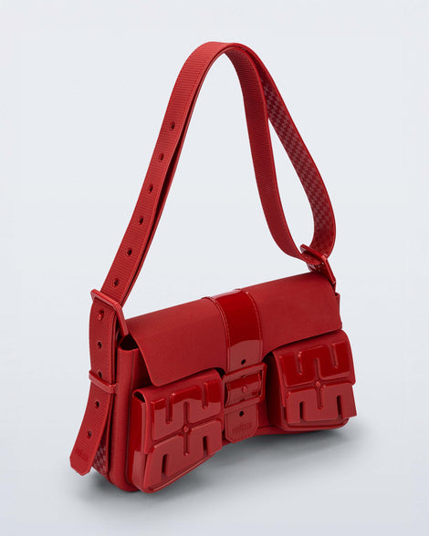 Angled view of a red Cargo bag with two small pockets on the front and an adjustable strap