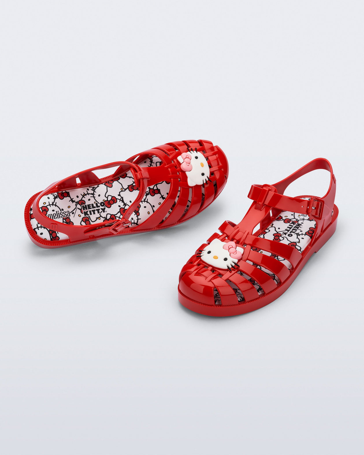 Top and angle view of a pair of red Possession + Hello Kitty and Friends fisherman sandals with Hello Kitty and friends on the upper