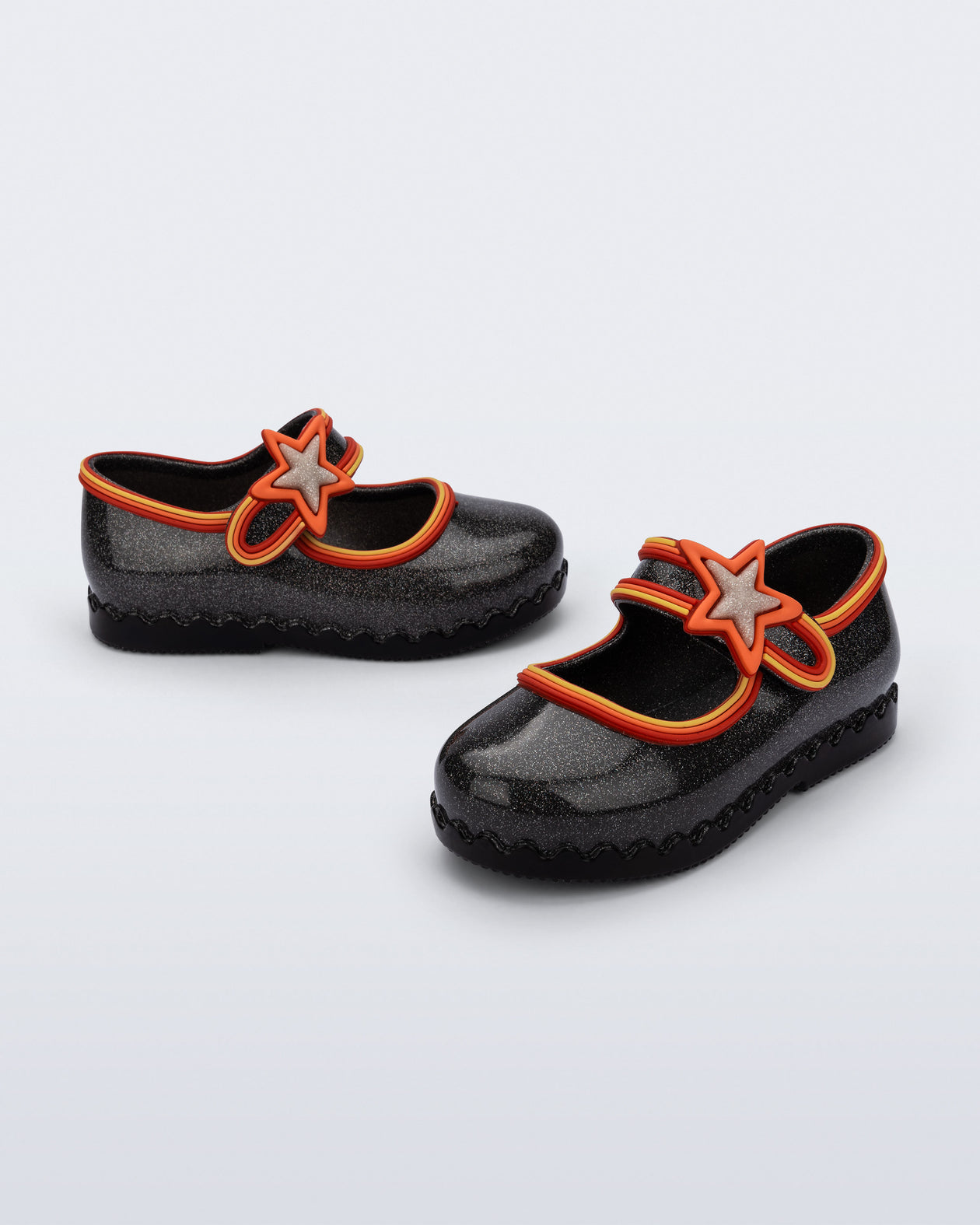 Side and angled view of a pair of glitter black Hip Ballerina Star baby flats with star on upper strap