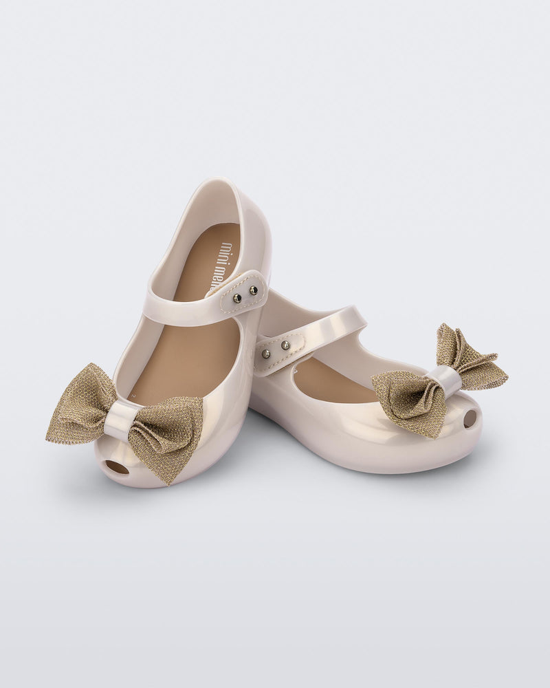 Angled view of a pair of beige Ultragirl Sweet baby ballerina flats