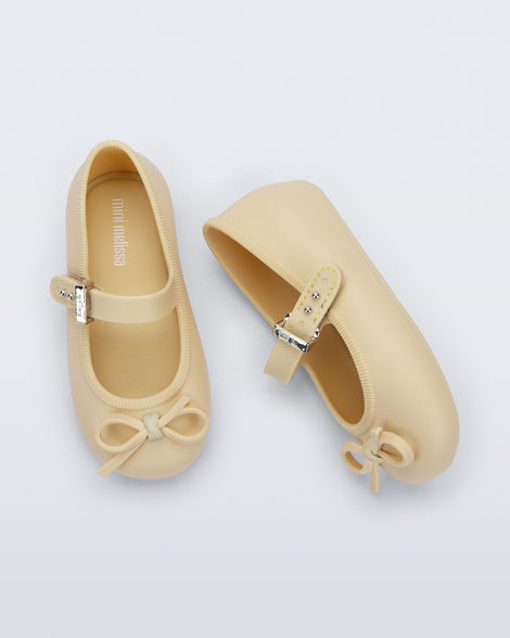 Side and top view of a pair of yellow Soft Ballerina Delicate Bow baby flats with top strap and bow