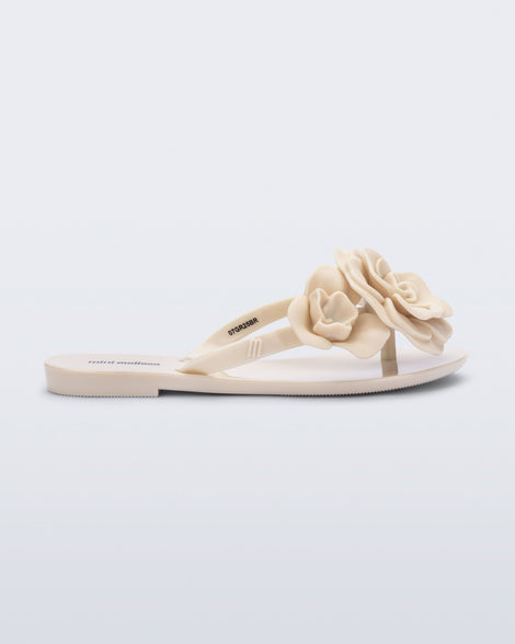 Side view of a beige Harmonic Petals kids flip flop with flowers
