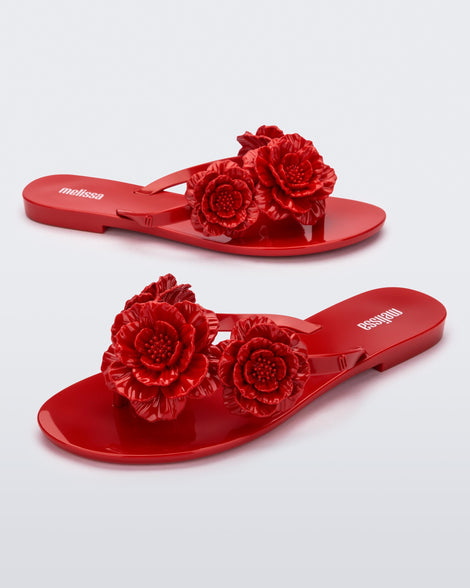 Angled view of a pair of red Harmonic Springtime women's flip flop with 3 red flowers.