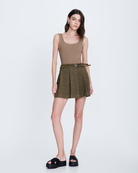 Model in a green skirt and beige tank top wearing a pair of black M Lover Cross Strap platform slides