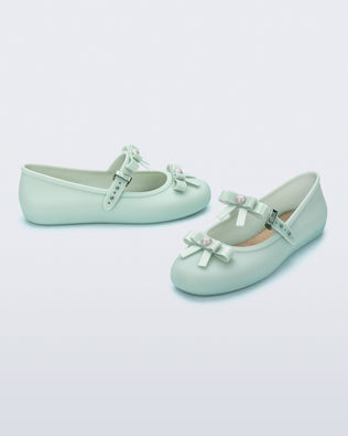 Angled view of a pair of green Soft Ballerina Bow flats with bows and a pearl in the center of each bow