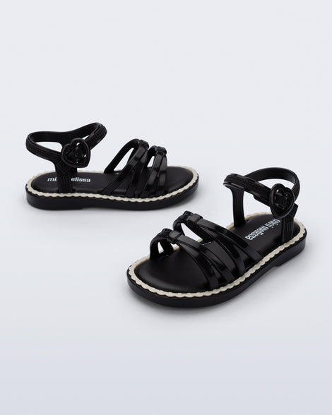 Side and angled view of a pair of black Aurora baby sandals with beige trim