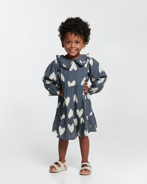 Child model in a blue dress wearing a pair of beige Cozy M Lover sandals