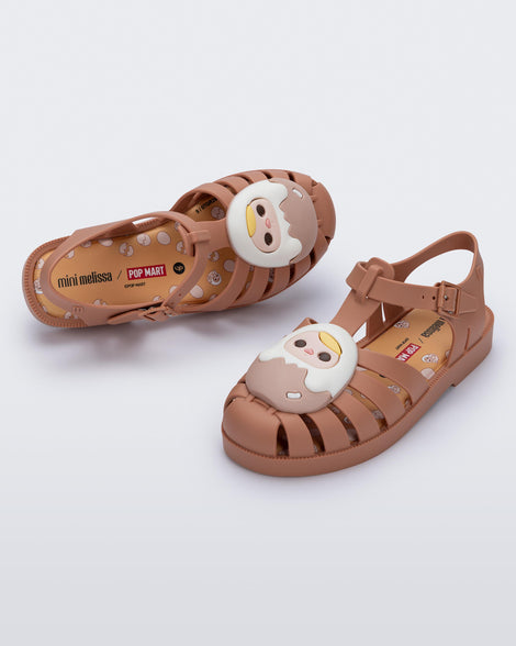 Top and angled view of a pair of beige Possession + Pop Mart Pucky fisherman kids sandal