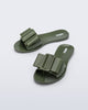 Angled view a pair of dark green Babe slide sandals with large bow on top.