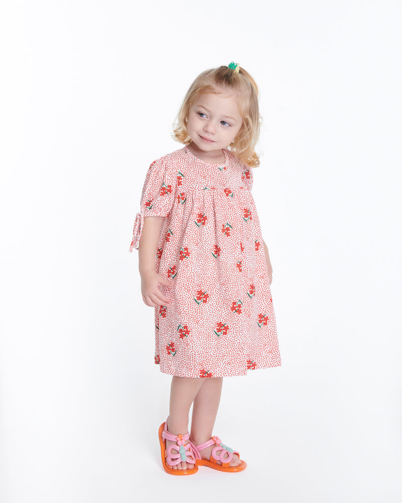 Child model in a pink dress wearing a pair of pink strap, orange sole Hip Butterfly baby sandals