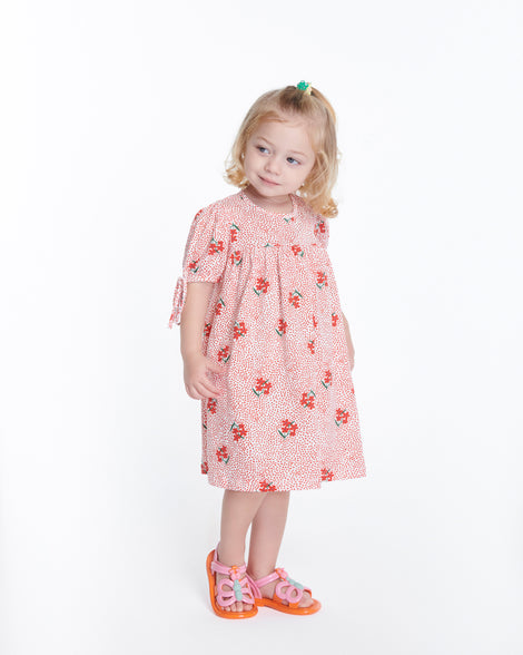 Child model in a pink dress wearing a pair of pink strap, orange sole Hip Butterfly baby sandals
