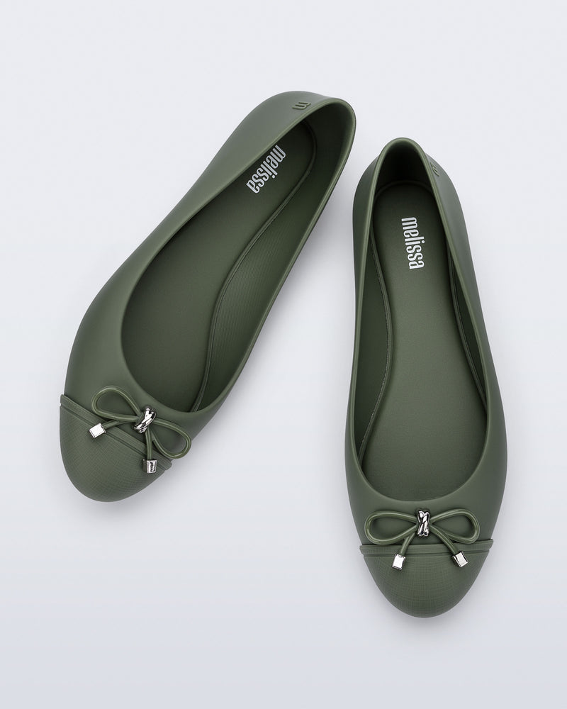An angled top view of a pair of green Melissa flats with a bow detail with gold accents on the bow