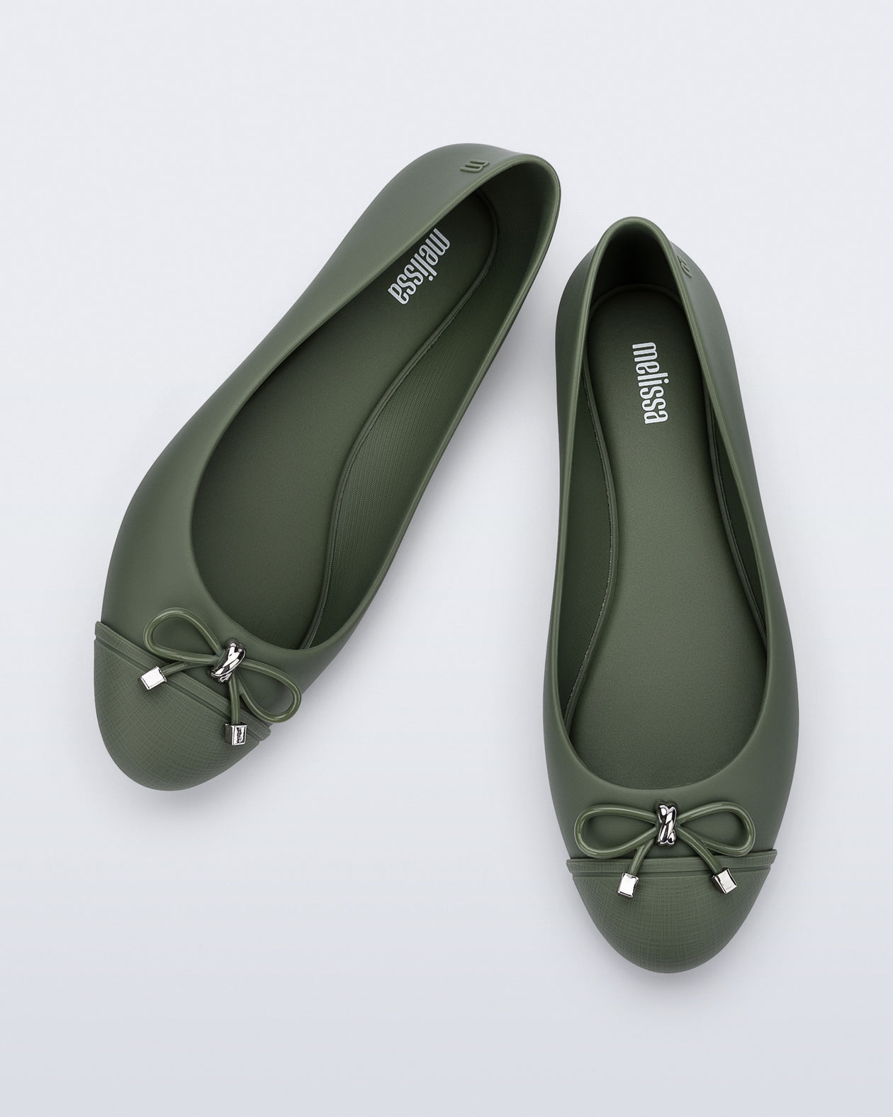 An angled top view of a pair of green Melissa flats with a bow detail with gold accents on the bow