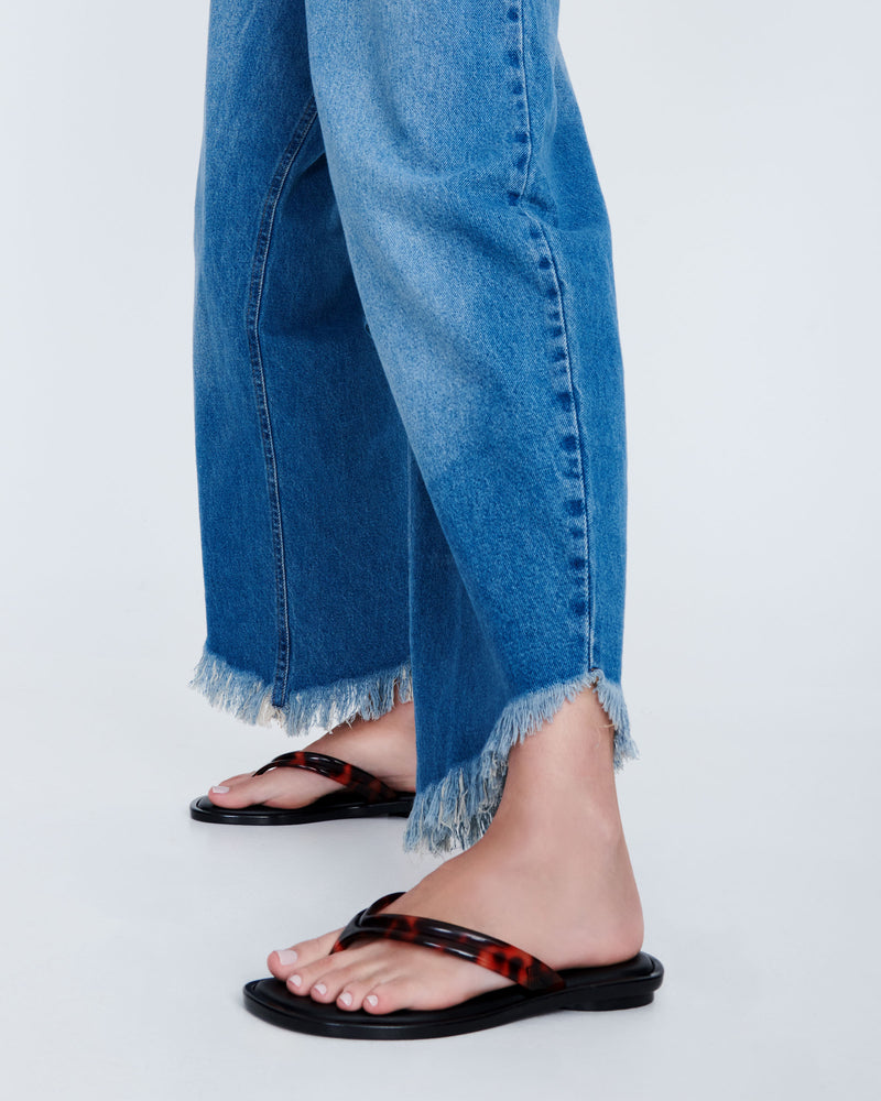 Model's legs in a pair of tortoise Wave Flip Flops with small heel and black sole