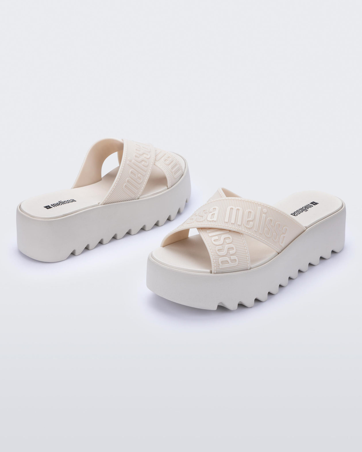 Back and side view of a pair of beige M Lover Cross Strap platform slides