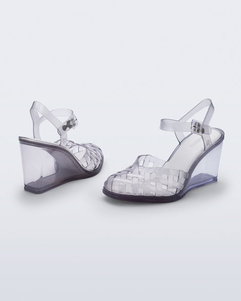 Side and back angled view of a pair of clear grey Agata wedge heel sandals with ankle strap