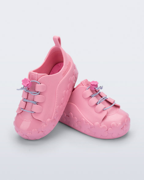 Angled view of a pair of pink Bloomy Sneaker with lilac laces and flower details on the sole
