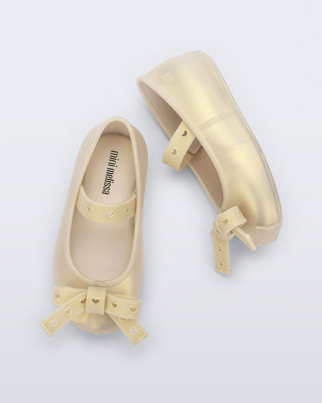 Top and side view of a pair of pearly beige Sophie Crush baby ballerina flats with bow