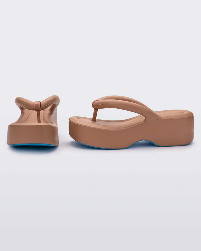 Front and side view of a pair of Melissa Free platform flip flops in brown with blue soles