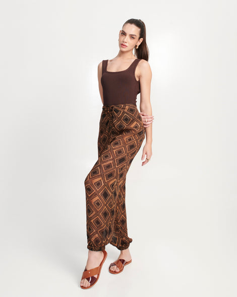 Model in a brown outfit wearing a pair of brown Essential Cross Slide sandals