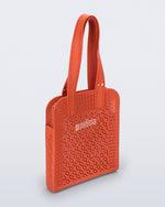 Angled view of an orange Harper bag with shoulder straps