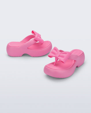 Side and angled view of a pair of pink Free Fuzzy Platform flip flops