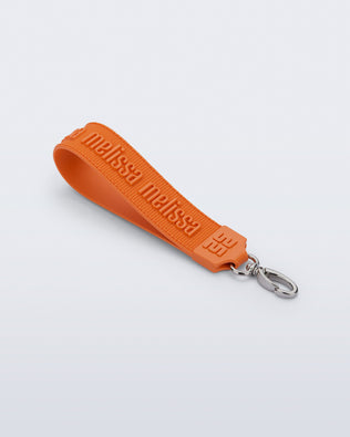 Angled flat view of an orange M Lover Charm with the Melissa logo