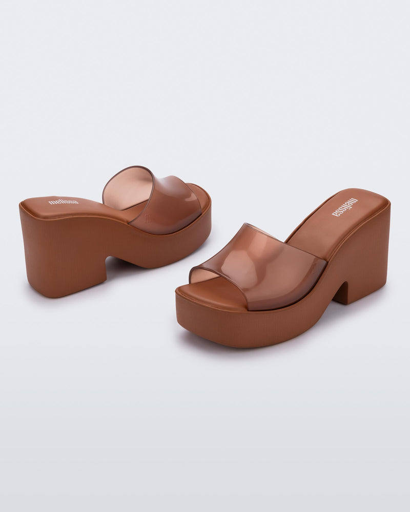 Back and side angled view of a pair of transparent brown Posh platform mule
