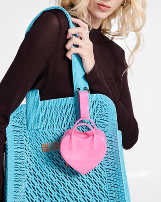 Model in a black shirt carrying a blue Harper bag with a pink Heartbeat Pocket charm on the strap