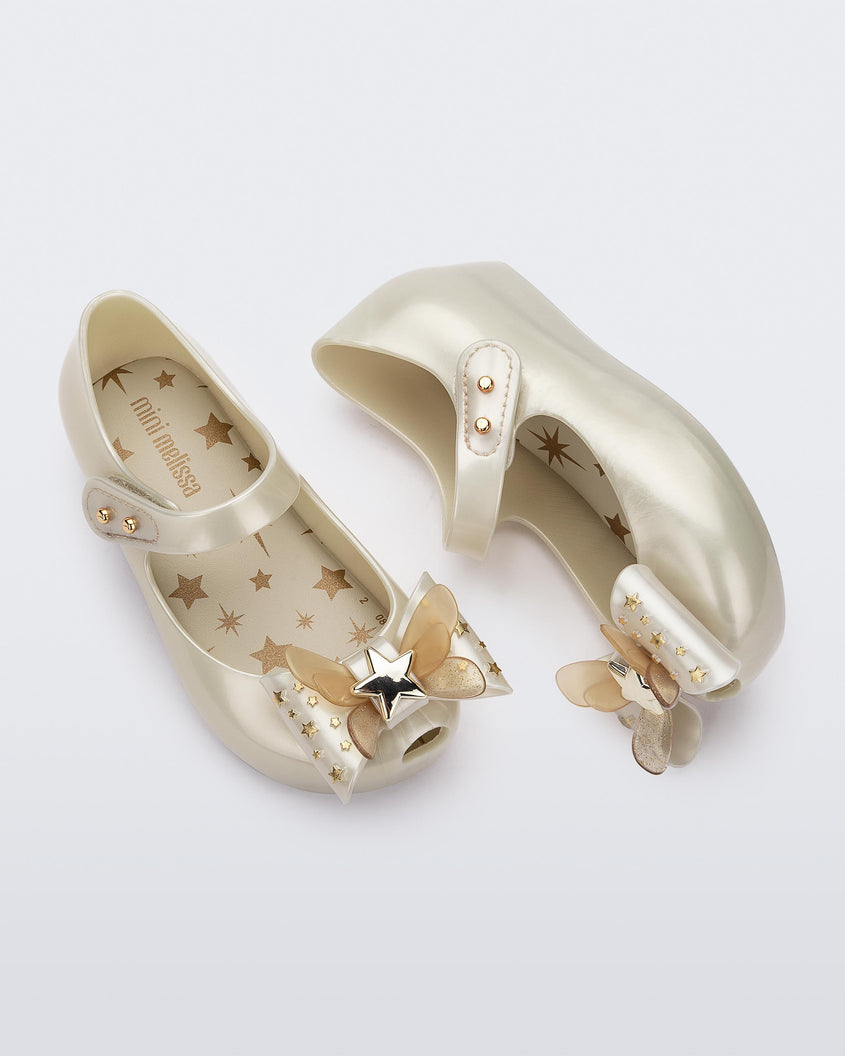 Top and side view of a pair of Mini Melissa Ultragirl peeptoe ballet flats for baby in white with star printed butterfly bow applique. 