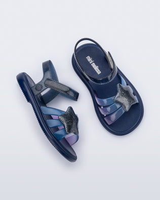 Side and top view of a pair of glitter blue Hip Sky baby sandals with a glitter blue star on top