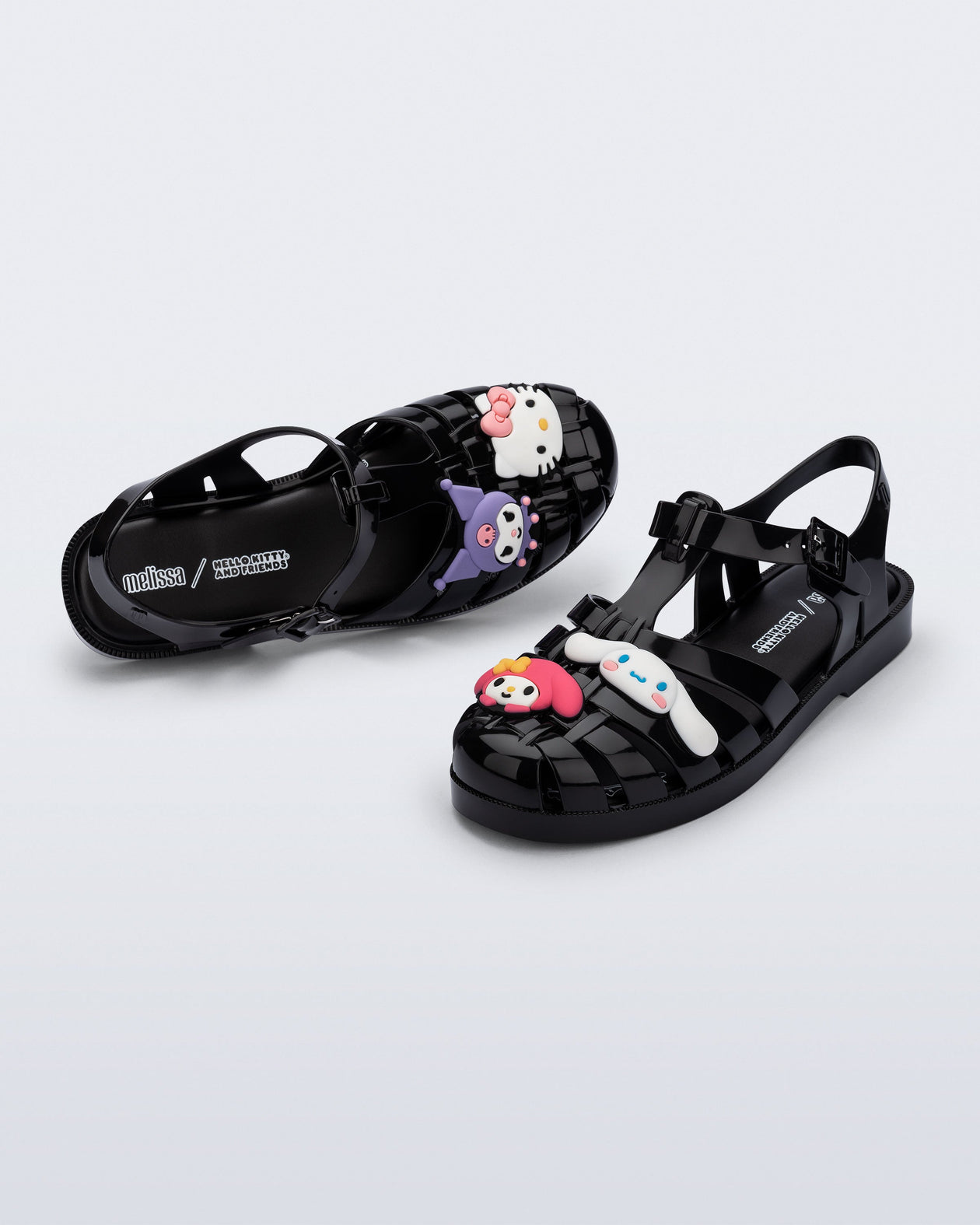 Top and angle view of a pair of black Possession + Hello Kitty and Friends fisherman sandals with Hello Kitty and friends on the upper